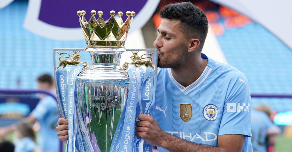Den spanske fotballspilleren Rodri kysser Premier League-trofeet i sølv og gull på et stadion mens han spilte for Manchester City Football Club i en lyseblå skjorte