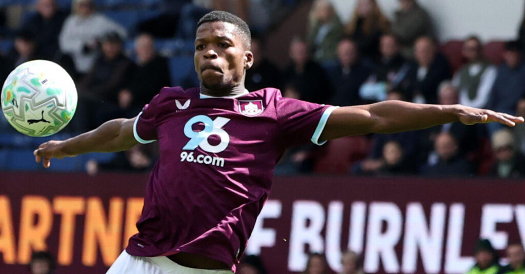 Fotballspiller Florentino Luis fra Premier League-laget Ipswich Town Football Club forme seg for å slå en ball med begge armer utstrakt mens han spilte for Burnley på deres Turf Moor-stadion i hjemmefargene deres hovedsakelig claret og ser på en hvit ball i luften