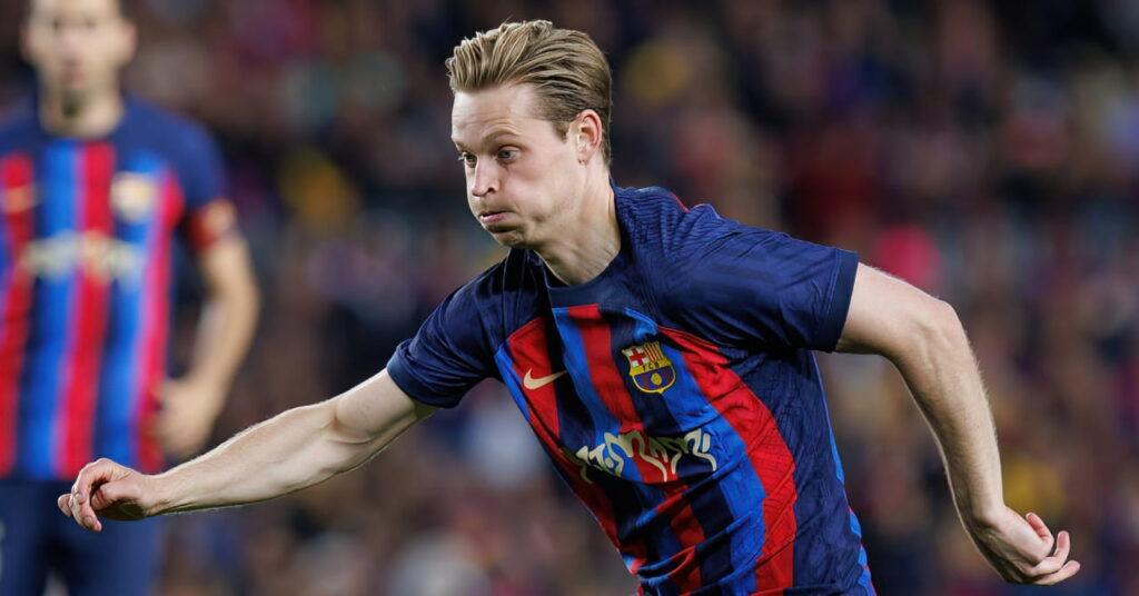Den nederlandske fotballspilleren Frenkie de Jong spiller for La Liga-laget Barcelona Football Club i en blå- og rødstripet topp mens han flytter en ball fremover på banen, puster ut kinnene og har på seg hvite støvler